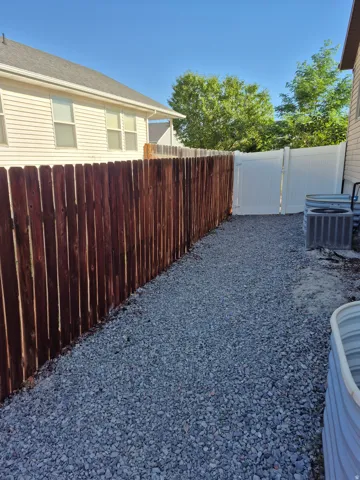 Gravel pathway bordered by a tall privacy fence