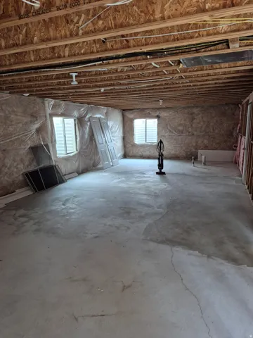 Unfinished basement space featuring exposed joists, two windows with blinds, and concrete flooring
