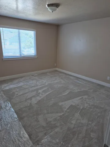 Carpeted room featuring a window with blinds, a flush mount ceiling light fixture, and neutral wall paint