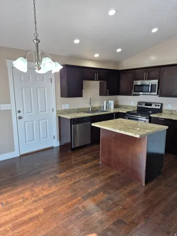 Kitchen featuring wood-finish flooring, dark wood cabinetry, and a central island with a stone countertop