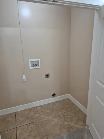 Utility closet featuring an in-wall water hookup for washer and dryer, finished with neutral tile flooring