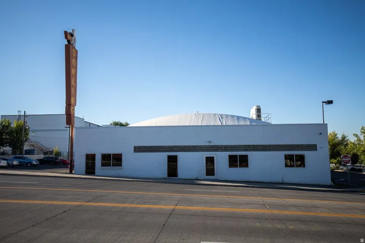 Commercial building featuring a white painted exterior, an arched roofline, multiple entryways, and a band of glass block windows