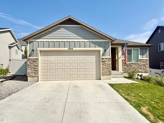 Single-story residence featuring a two-car garage, stone and siding exterior, and a concrete driveway