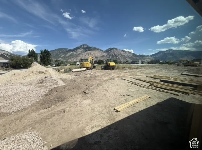 Expansive lot featuring a clear building site, mountain backdrop, and bright blue sky