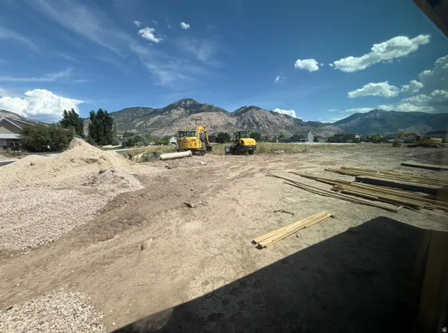 Expansive lot featuring a clear building site, mountain backdrop, and bright blue sky