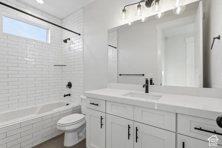 Modern bathroom featuring a white subway tile tub surround with a horizontal window, a white vanity with a single basin sink, a large wall-mounted mirror, and black plumbing fixtures with coordinating hardware