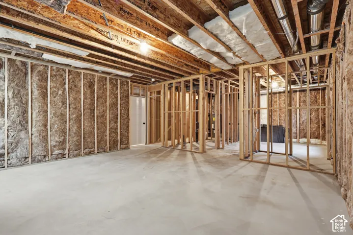 Unfinished basement space featuring exposed wood framing, concrete flooring, and visible insulation