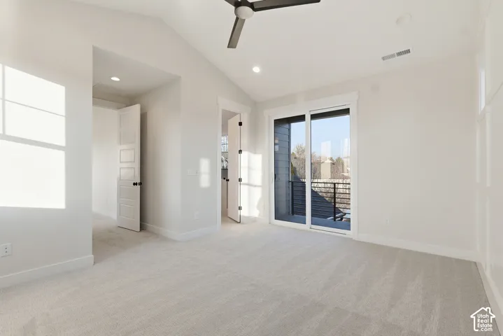 Spacious bedroom featuring light-toned carpeting, a vaulted ceiling, and recessed lighting