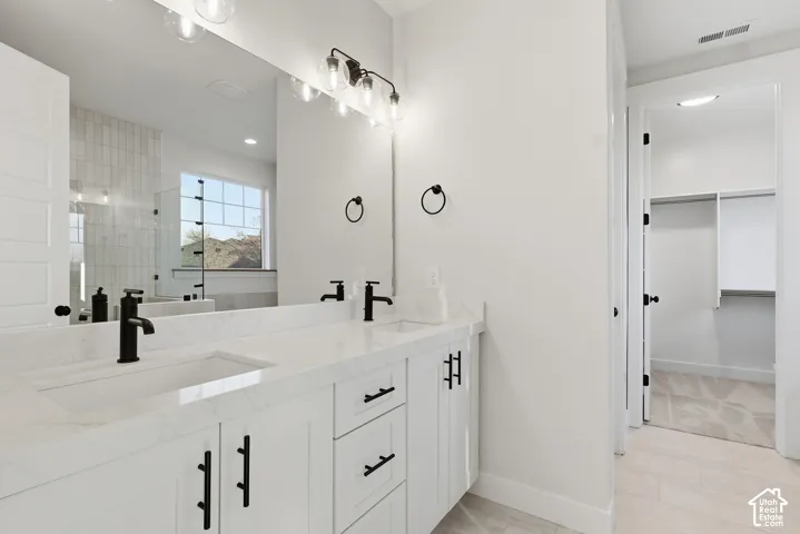 Dual vanity featuring integrated sinks, white cabinetry, matte black hardware, and an expansive mirror