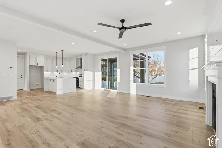 Open-concept living space featuring wide-plank wood-finish flooring, recessed lighting, and a contemporary ceiling fan