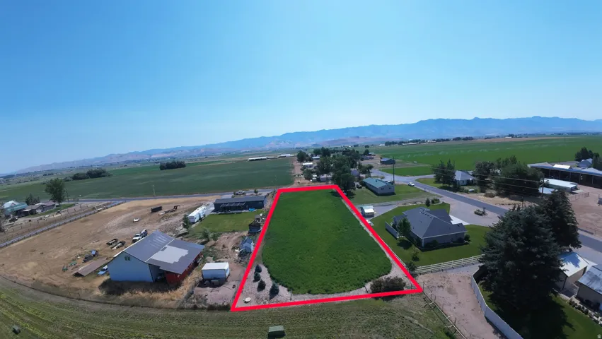 Expansive green land parcel with clear boundaries, surrounded by open fields and distant mountains