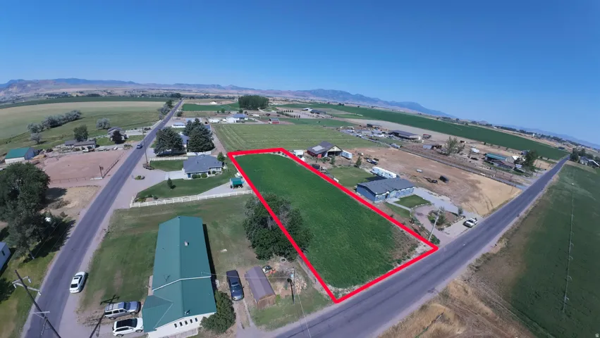 Expansive rectangular lot featuring green vegetation, bordered by paved roads on two sides