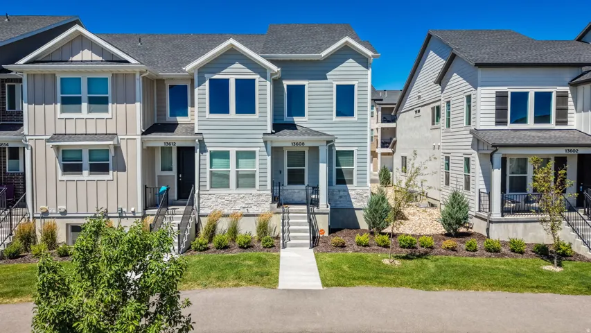 Modern townhome with light blue siding, white trim, and stone accents