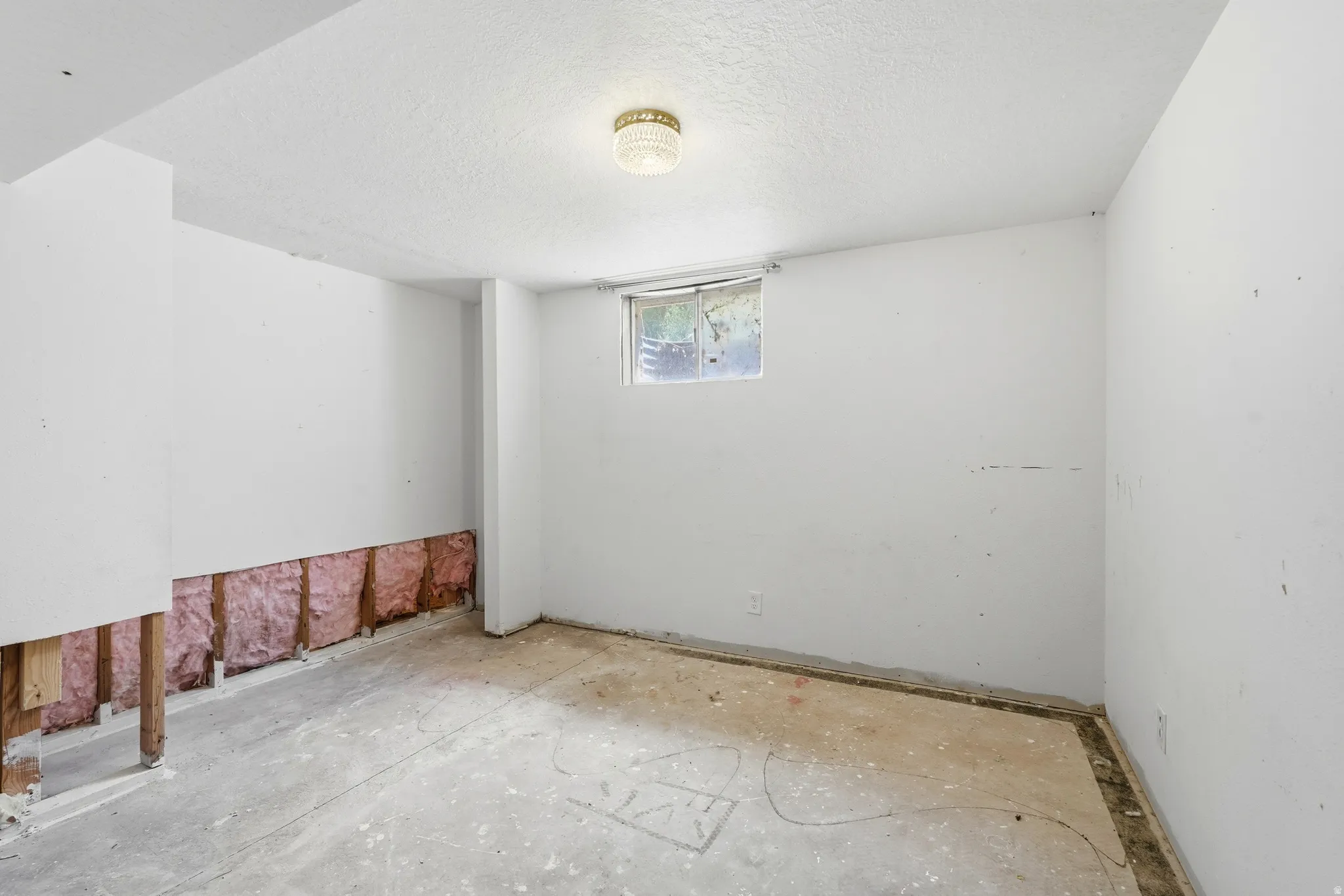 Lower level room featuring a window, exposed insulation, wood framing, and a concrete floor