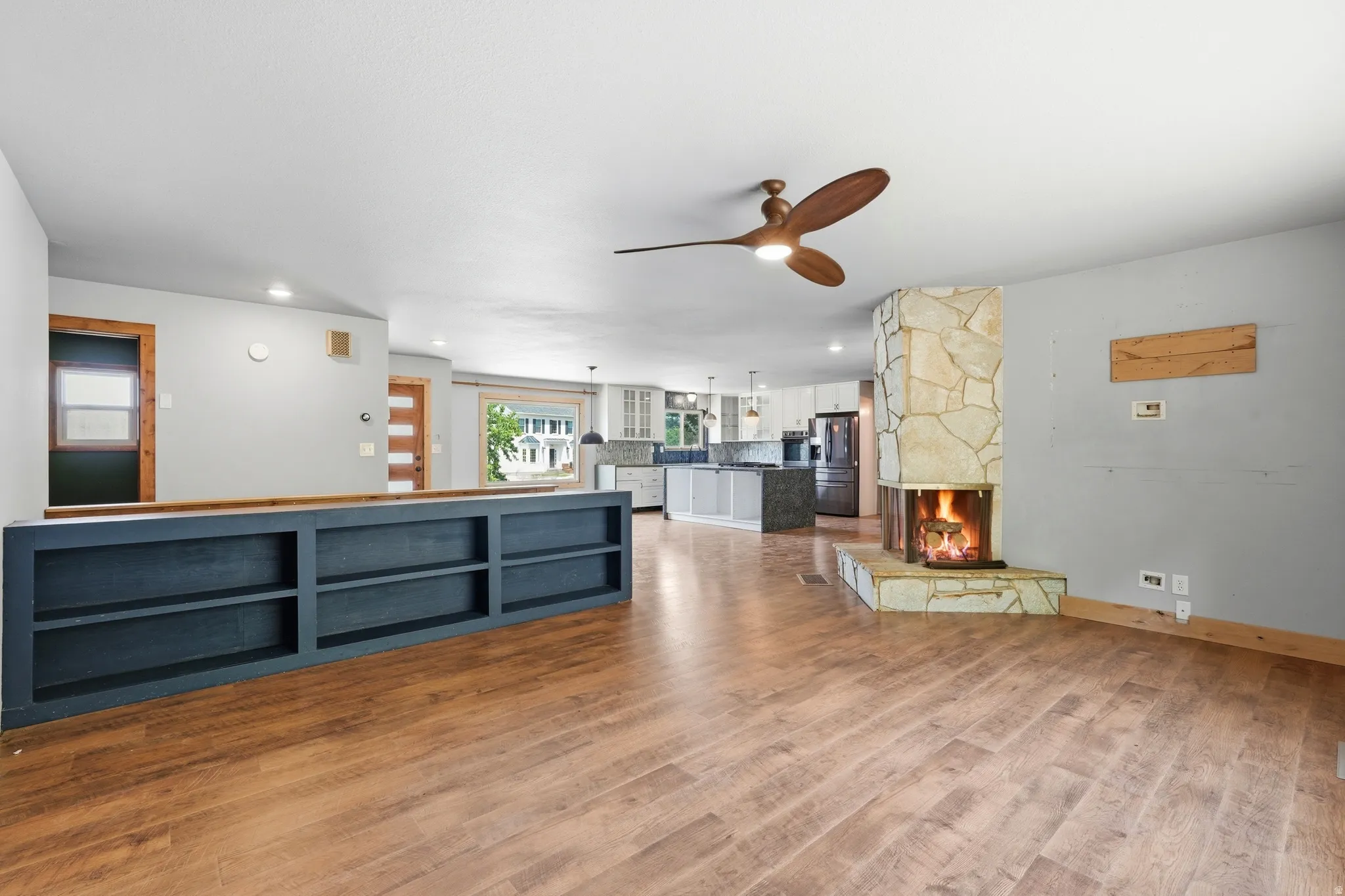Expansive living area featuring wood-finish flooring and a corner stone-faced fireplace