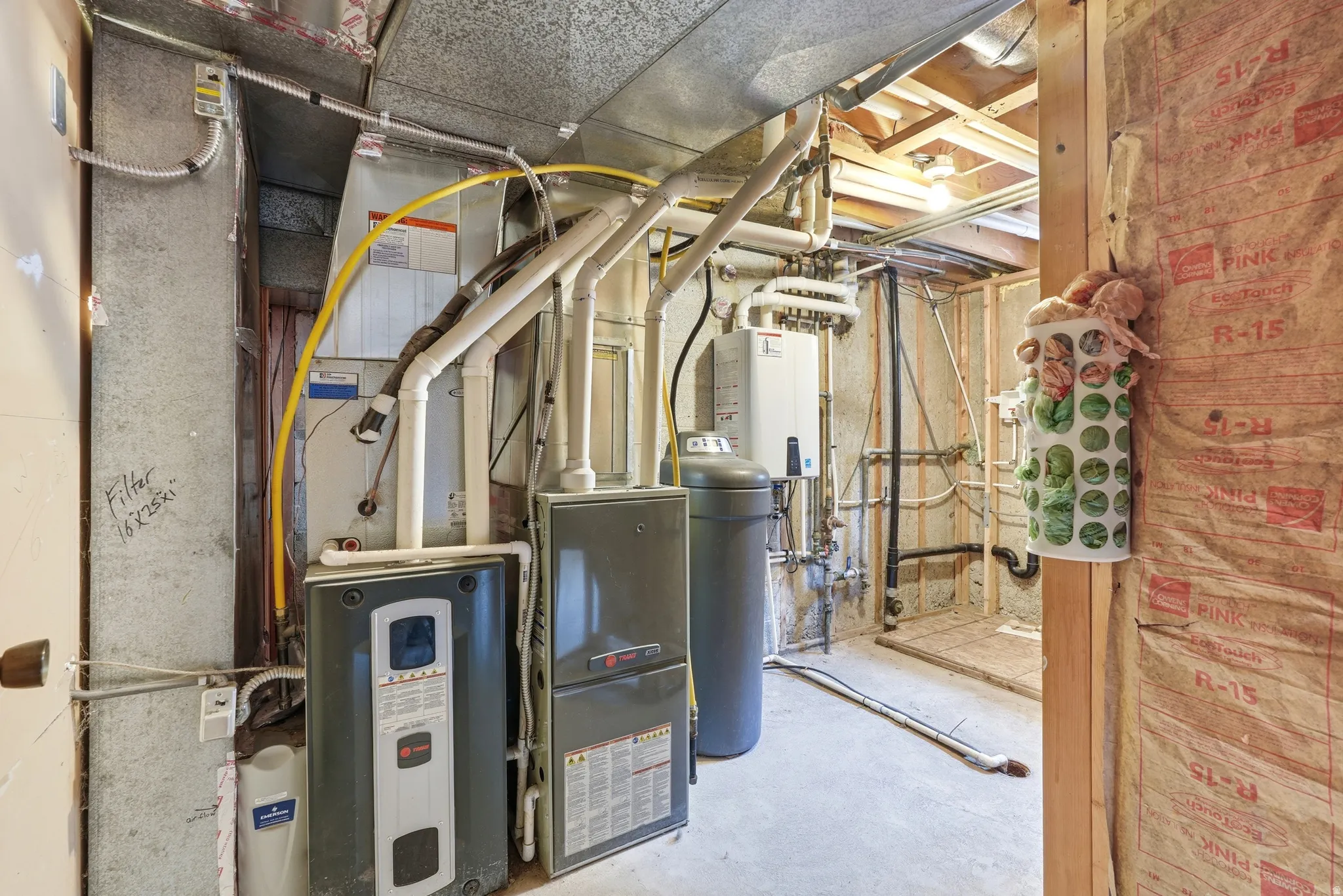 Utility room featuring a water heater, furnace, water softener, tankless water heater, and exposed ceiling joists