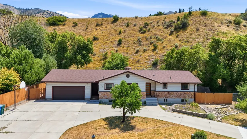 Ranch-style residence featuring a detached two-car garage, a wide concrete driveway, and a fenced side yard
