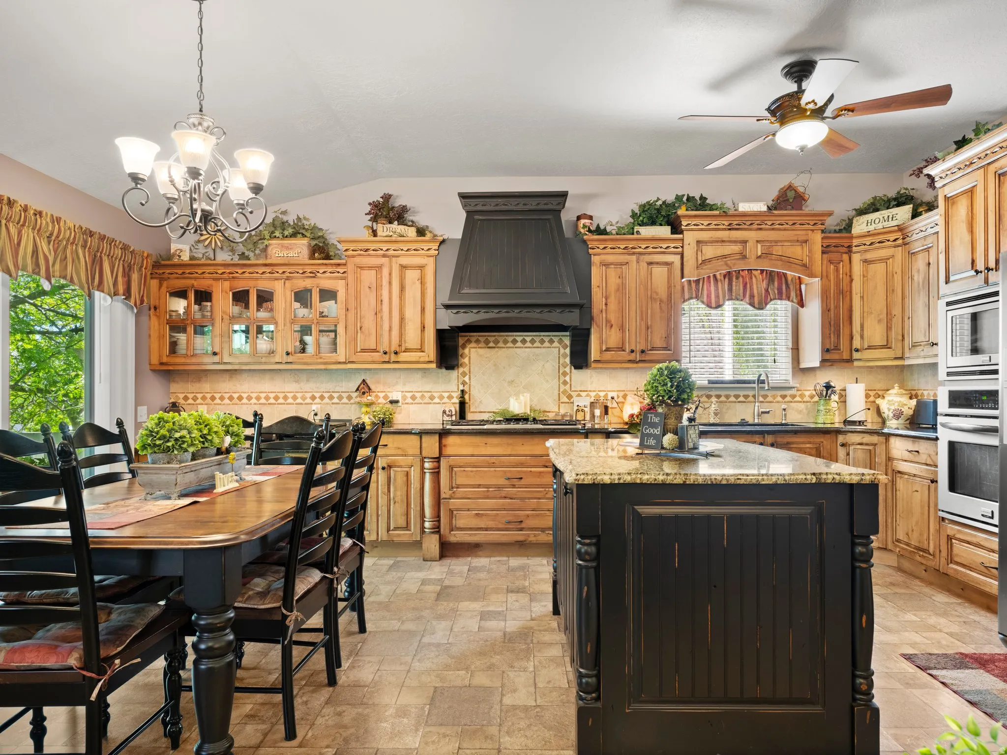 Spacious kitchen featuring extensive wood cabinetry, a large custom kitchen island with stone countertops, built-in wall oven and microwave and pantry.