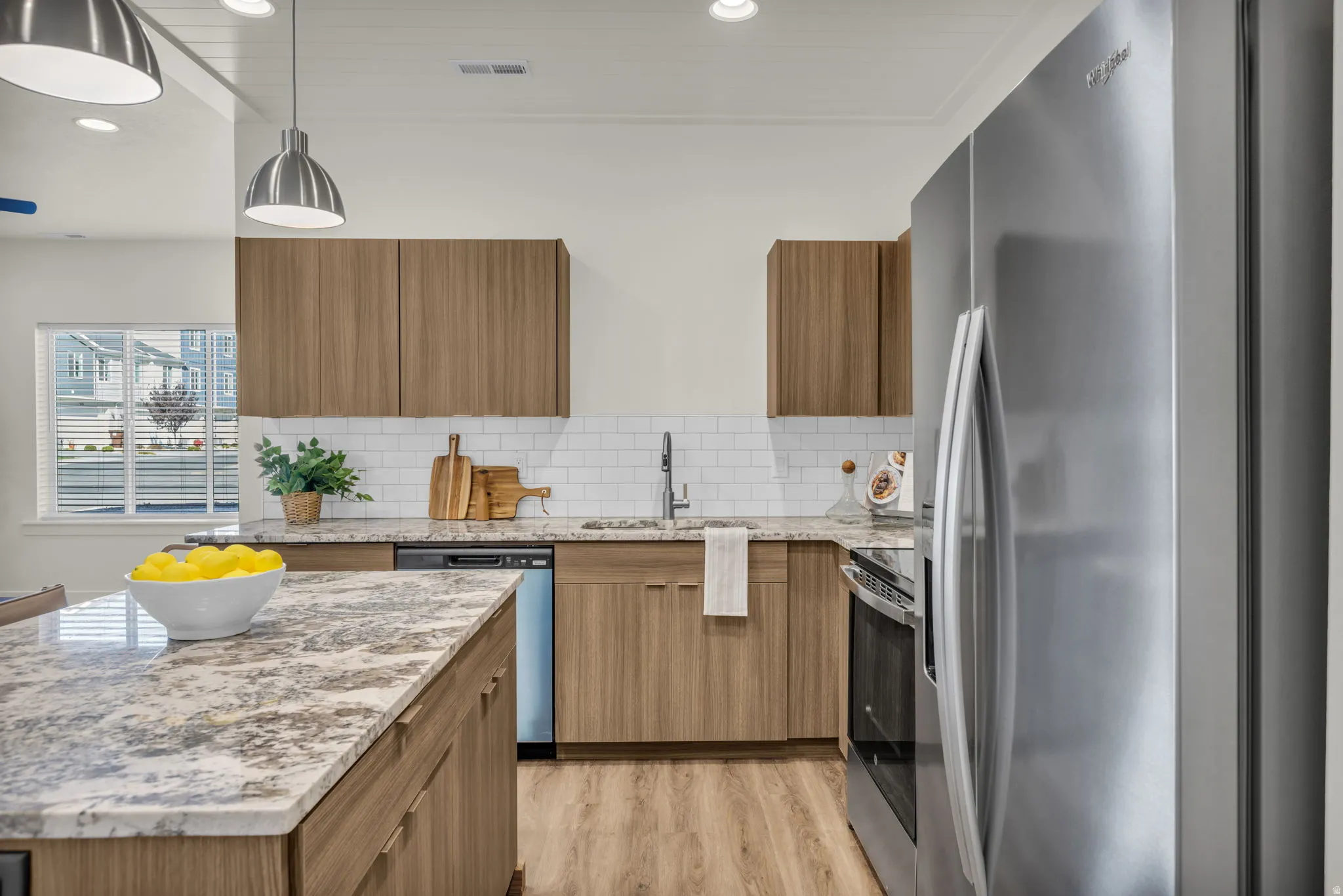 Kitchen featuring an island with stone countertops, wood-finish cabinetry, stainless steel appliances, white subway tile backsplash, and wood-finish flooring