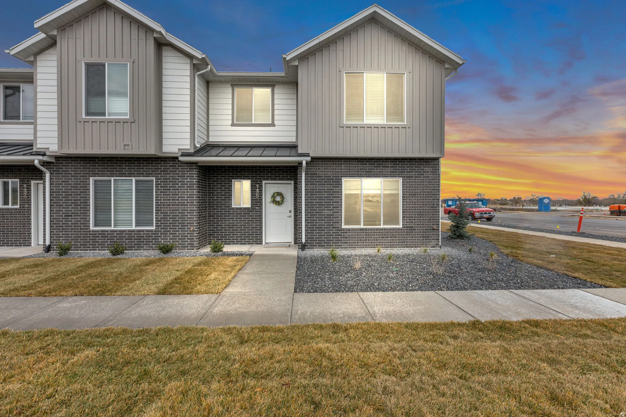 Modern exterior featuring grey brick veneer, vertical panel siding, horizontal siding, and multiple windows