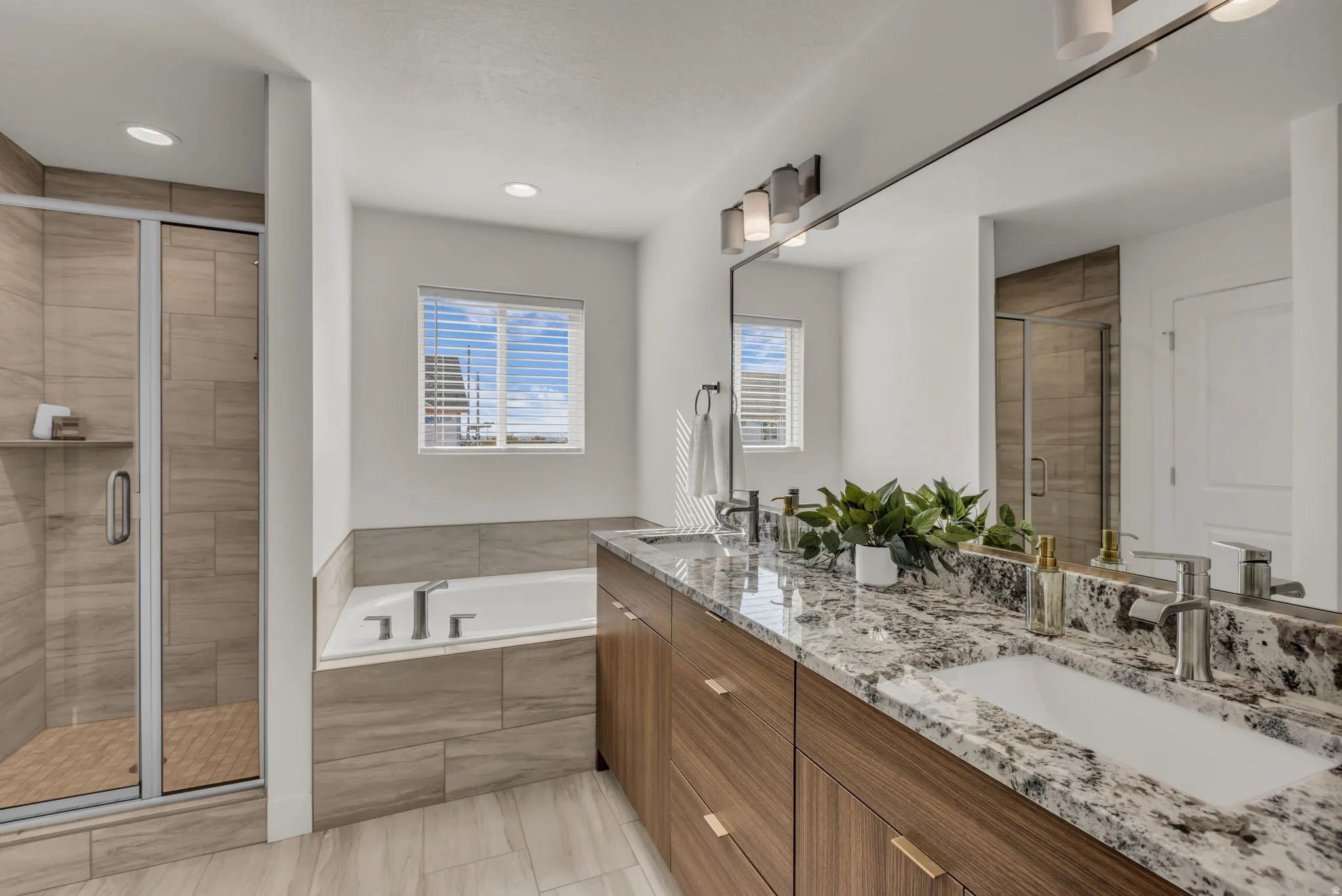 Contemporary bathroom featuring a double vanity with granite countertops, wood-finish cabinetry, and undermount sinks