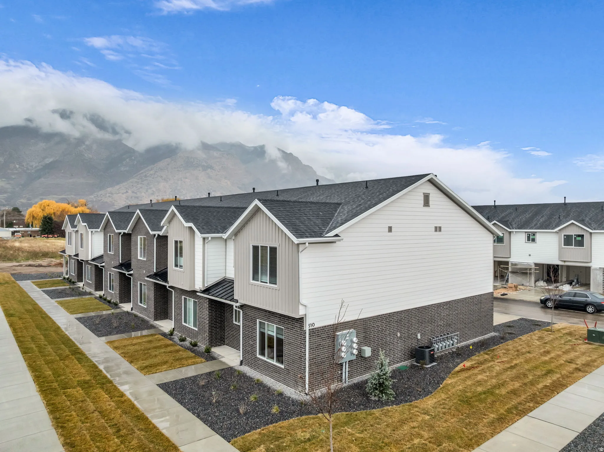 Contemporary townhome exteriors featuring dark gray brick and light siding