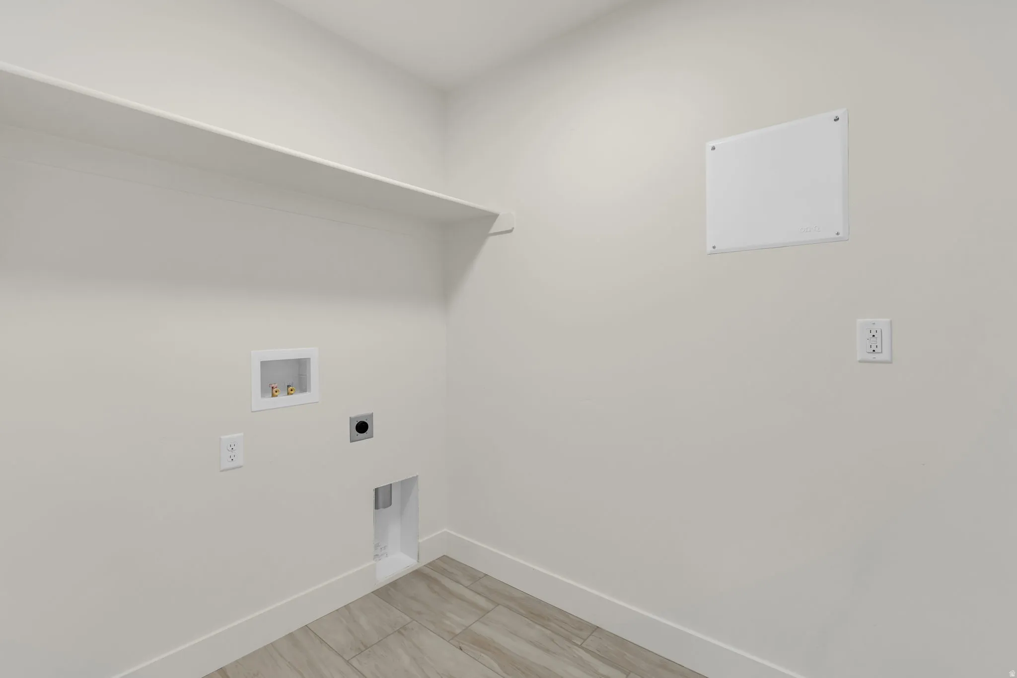 Dedicated utility area featuring a built-in shelf, plumbing hookups, electrical outlets, and wood-finish flooring