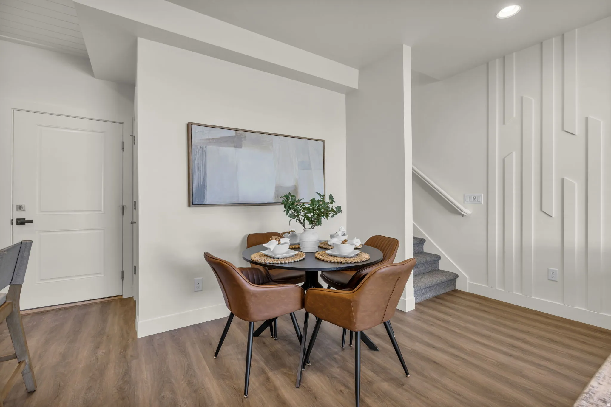 Open-concept dining area featuring wood-finish flooring, a contemporary accent wall, recessed lighting, and a neutral color palette
