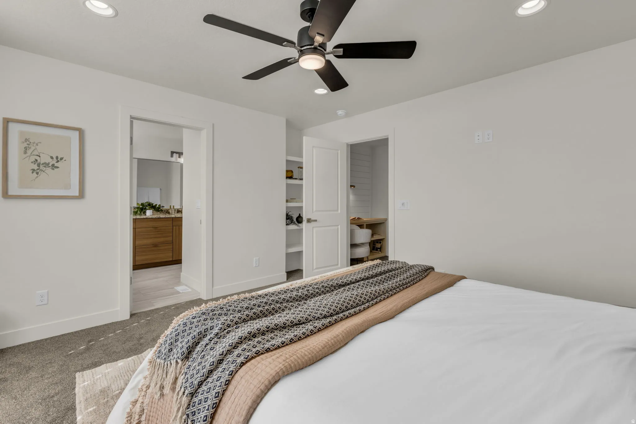 Recessed ceiling lighting, ceiling fan with light fixture, built-in shelving, wood-finish vanity, and hard-surface flooring in a bright interior space