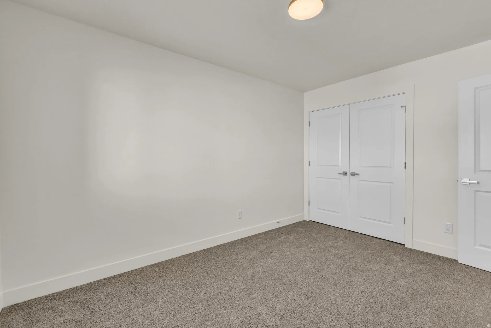 Neutral toned room with wall-to-wall carpeting and white baseboards