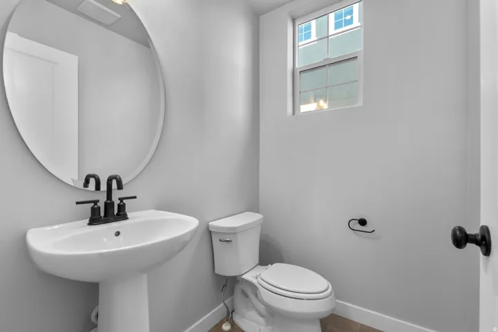 Pedestal sink featuring a matte black faucet set and an oval wall mirror