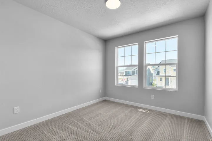 Room featuring two grid-pattern windows, light gray walls, white baseboards, and neutral-toned carpet flooring