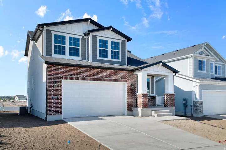 Contemporary two-story residence featuring a brick and siding exterior, an attached two-car garage, a covered entry porch with columns, and multiple paneled windows