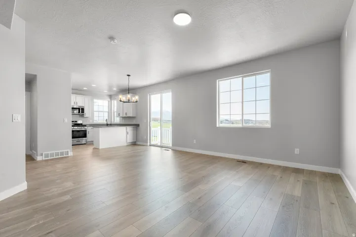 Spacious room featuring light wood-finish flooring, a large grid-pane window, and a sliding glass door