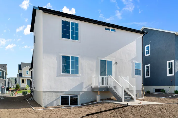 White stucco exterior with a dark roofline, featuring multiple windows with grid patterns