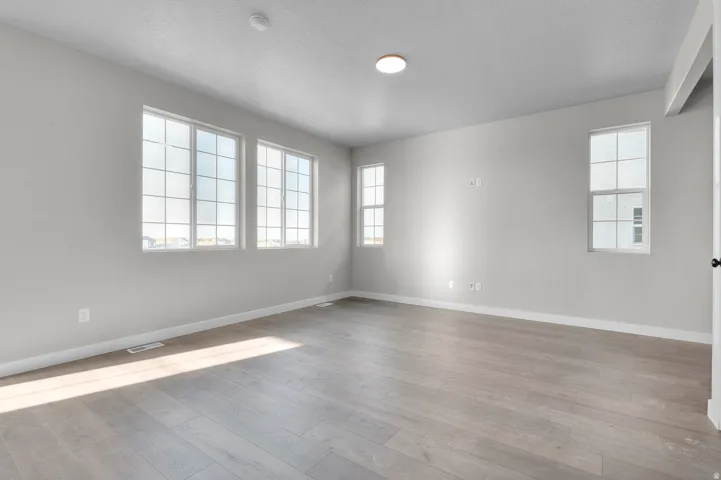 Spacious room featuring light wood-finish flooring, white baseboards, and neutral wall paint
