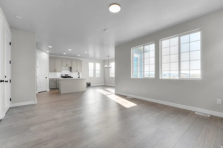 Open-concept living area with wood-finish flooring, recessed lighting, and large windows