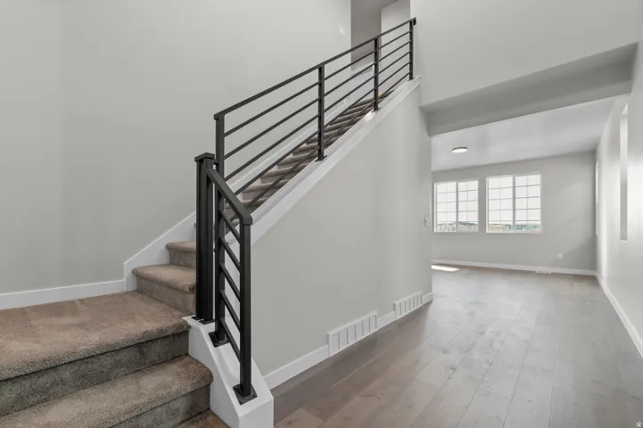 Modern staircase featuring a black metal horizontal railing system and carpeted treads