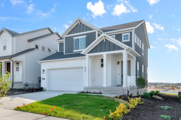 Two-story residence featuring a two-tone exterior with white brick and dark gray siding