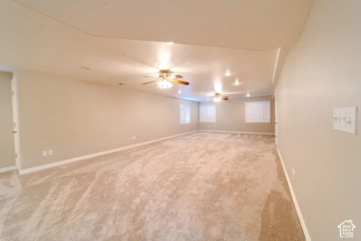 Spacious room featuring plush carpeting, multiple windows with blinds, recessed lighting, and ceiling fans