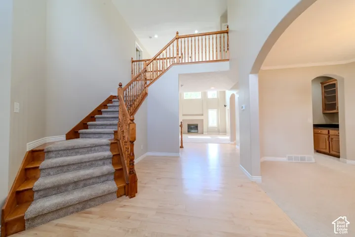 Two-story foyer featuring a grand staircase with wood newel posts and spindles, carpeted treads, and light wood-finish flooring