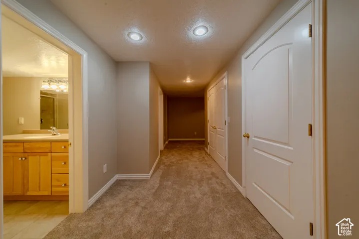Hallway featuring recessed lighting, light beige carpeting, and white baseboards