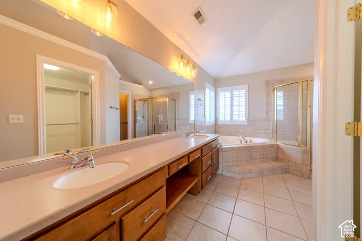 Dual vanity with integrated sinks, tiled flooring, built-in soaking tub, separate shower enclosure, and louvered window treatments