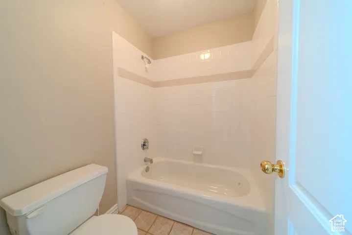 Bathroom featuring a white bathtub with chrome fixtures, white subway tile surround, and a decorative tile accent band