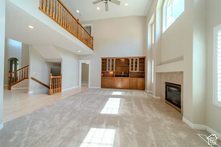 Expansive living space featuring vaulted ceilings, a built-in entertainment center with wood cabinetry, and a gas fireplace with a tile surround