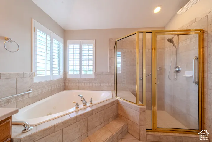Jetted soaking tub and a glass-enclosed shower with gold-tone framing