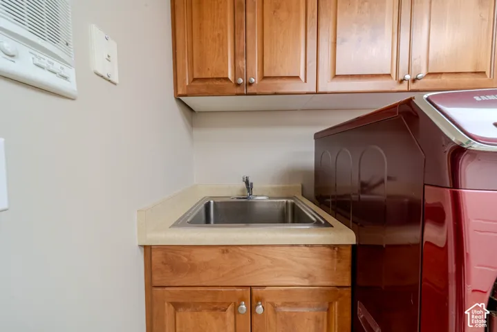 Utility sink with a chrome faucet, set into a light-toned countertop, complemented by wood-finish cabinetry