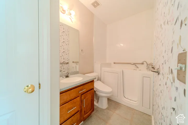 Bathroom featuring a walk-in tub with grab bars, a single vanity with a light-colored countertop, and a built-in mirror