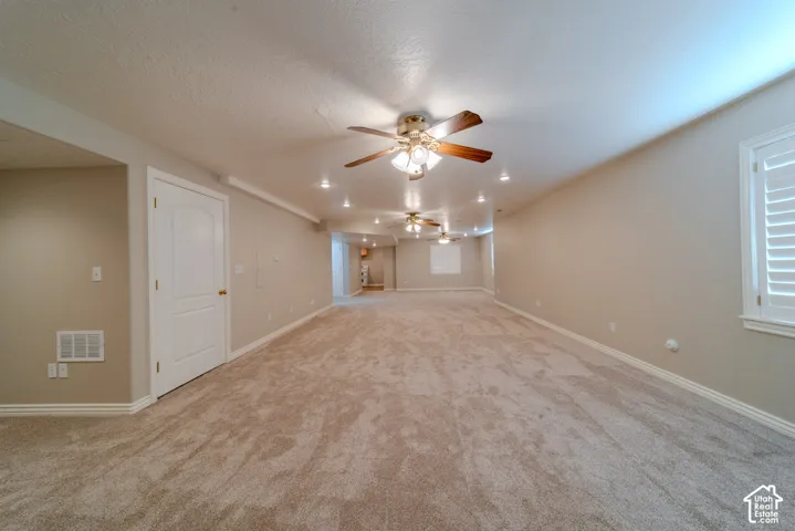 Spacious room featuring plush carpeting, recessed lighting, multiple ceiling fans, neutral wall tones, and plantation shutters