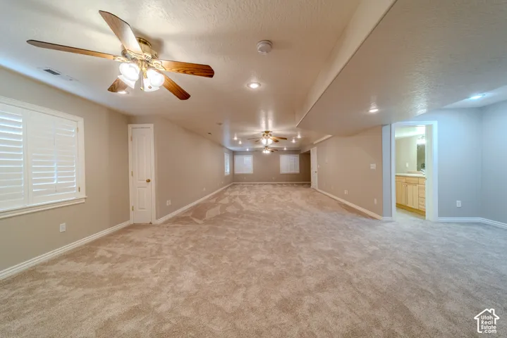Expansive carpeted room featuring multiple ceiling fans with integrated lighting, recessed lighting, and white plantation shutters